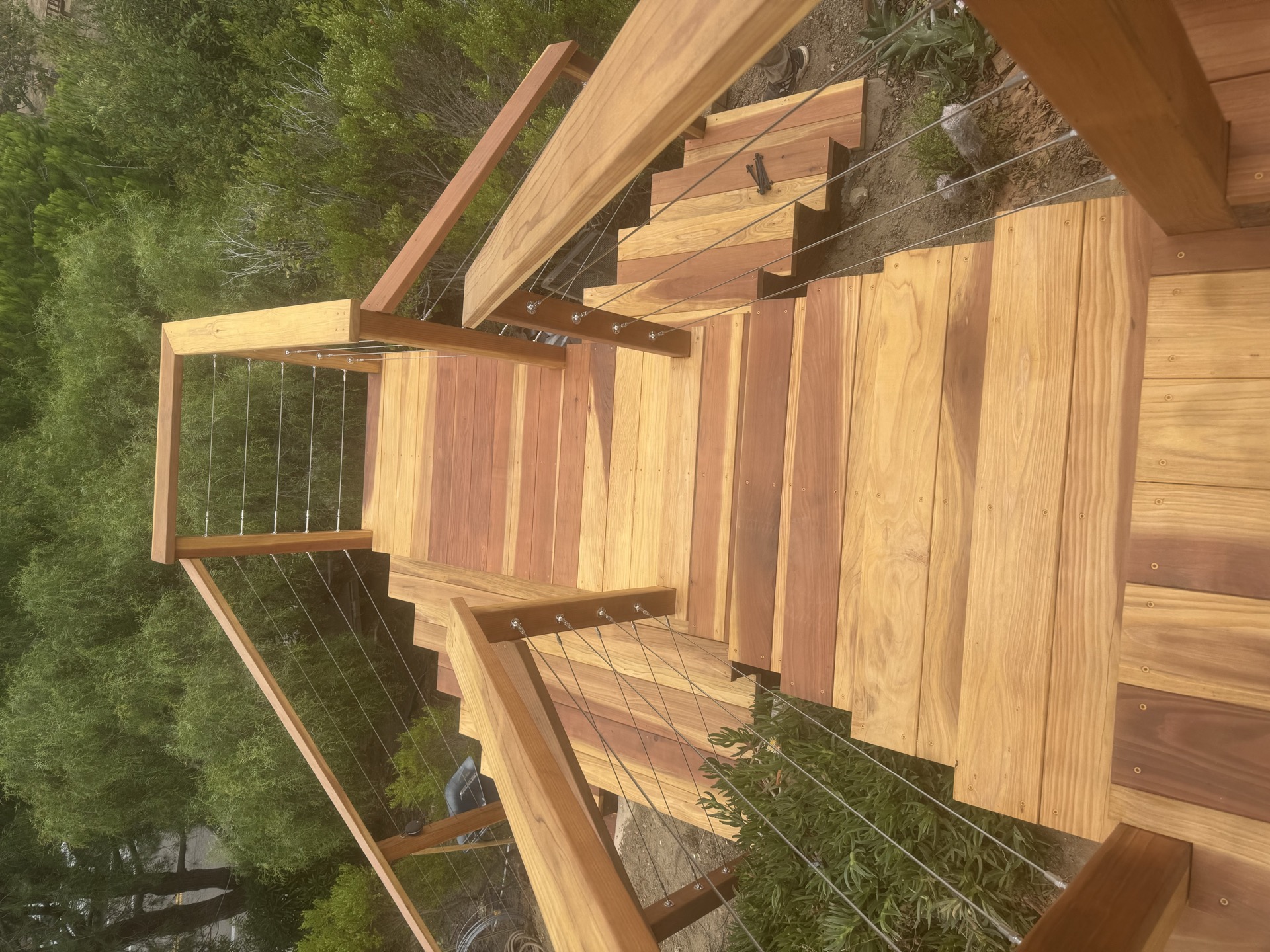 Deck stairs with cable railing surrounded by mature trees