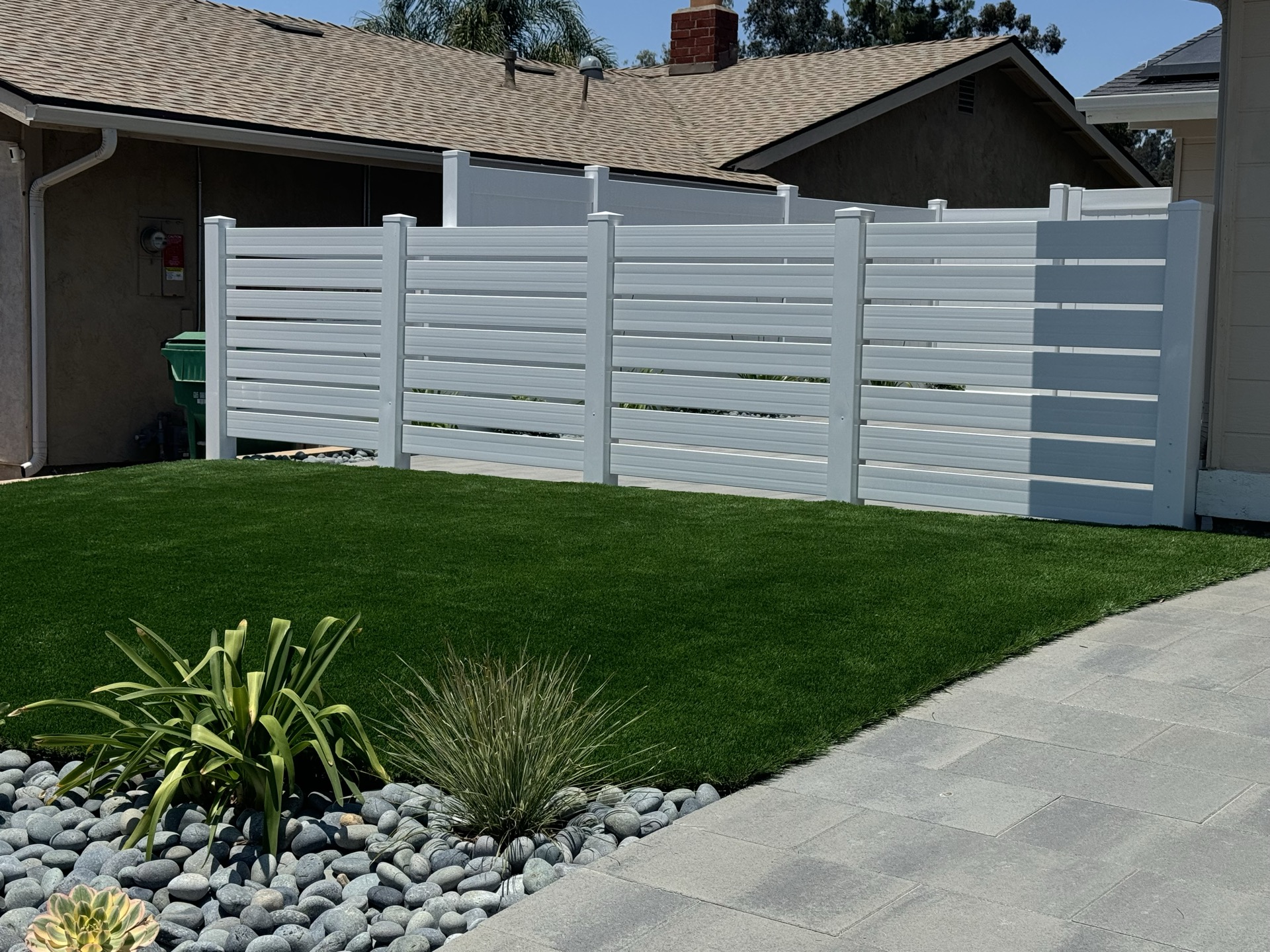 Lush lawn with vinyl fence and river rock in San Diego